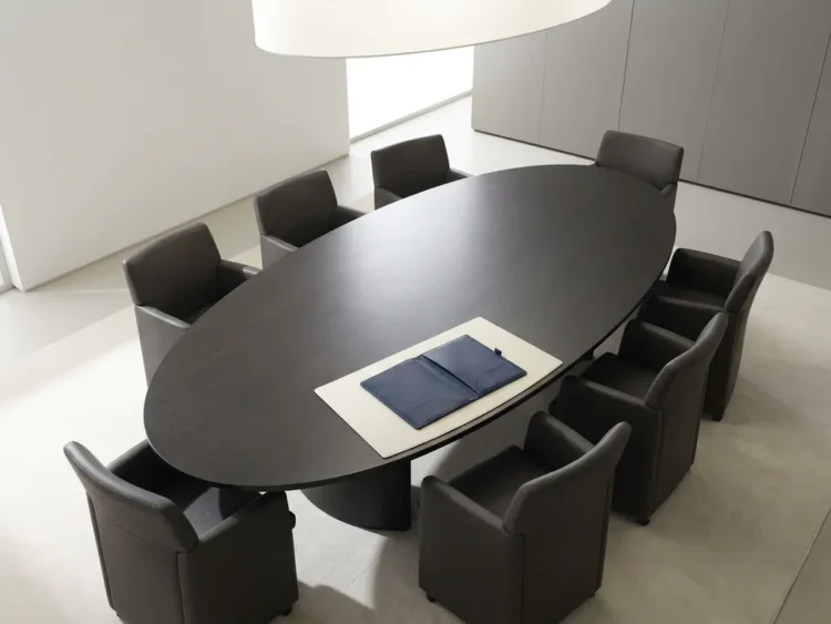 Ovale vergadertafel in marineblauw en houtskool met symmetrisch geplaatste leren stoelen en een open dossier aan het hoofd.