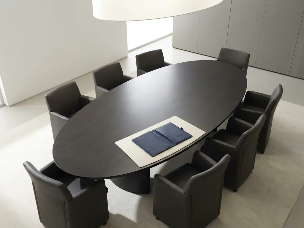 Ovale vergadertafel in marineblauw en houtskool met symmetrisch geplaatste leren stoelen en een open dossier aan het hoofd.