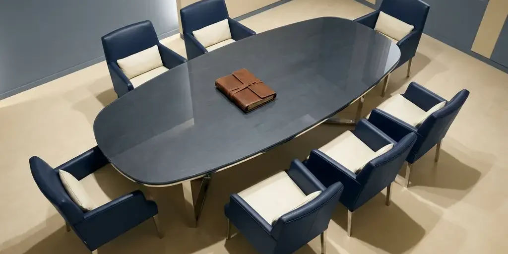 Ovale vergadertafel met acht leren stoelen en een gesloten dossier in het midden, gefotografeerd vanuit vogelperspectief.